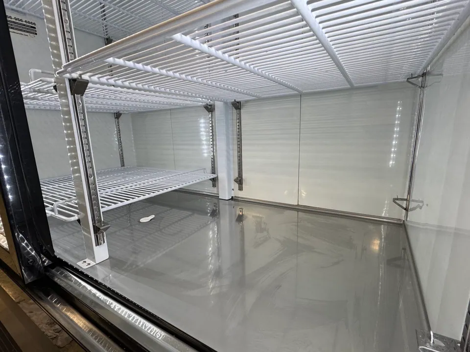 Clean commercial refrigerator interior with polished surfaces and shelves